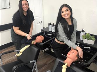 Two cosmetology students practicing hair washing on their mannequin heads