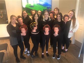 Group of female cosmetology students posing for a picture with their mannequin heads